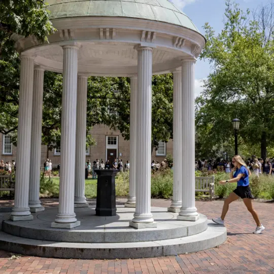 Student walking toward the Old Well