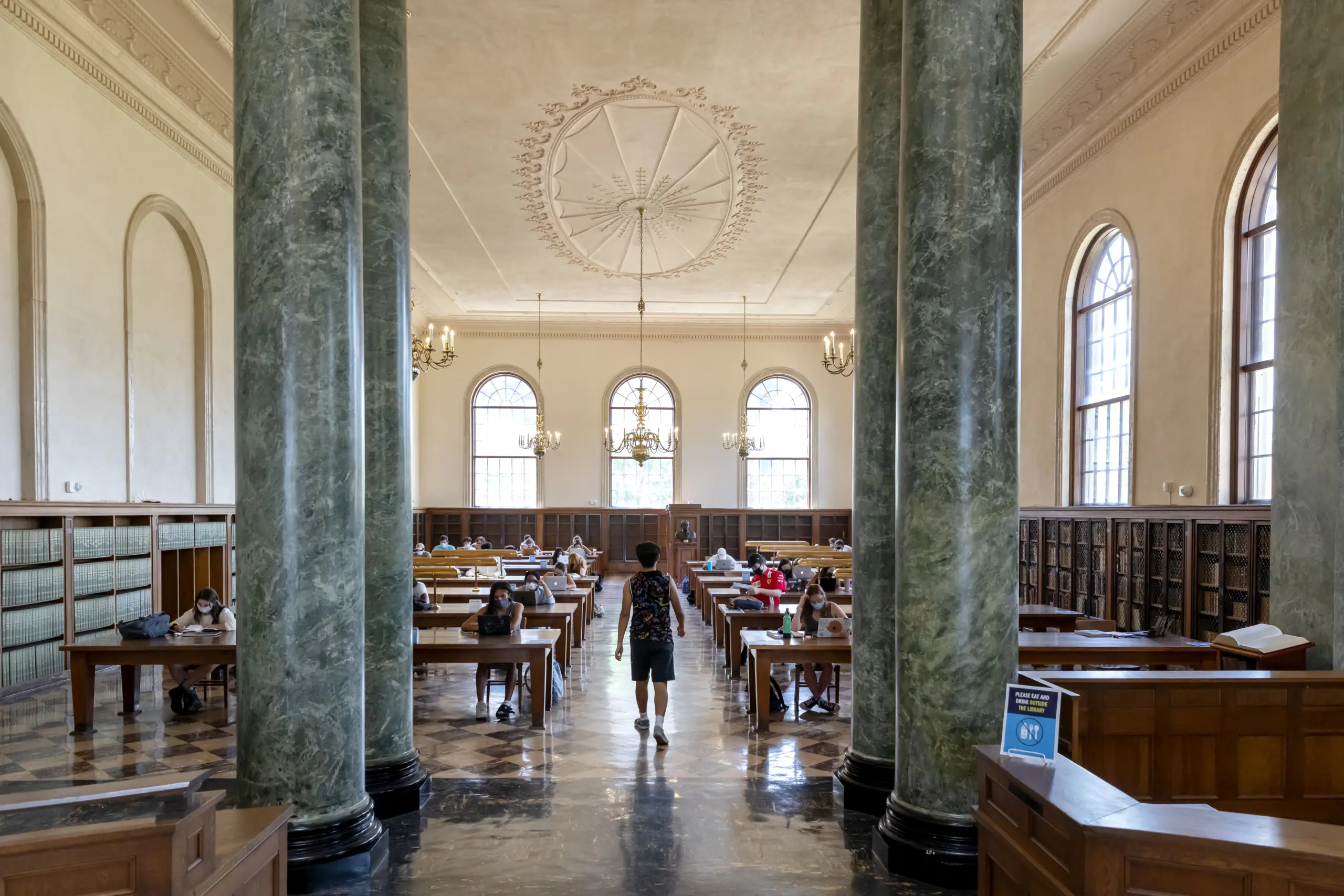 Student walking past study tables in Wilson Library